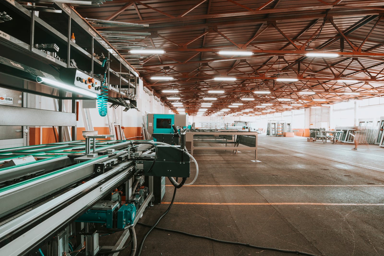 Wide factory interior with conveyors and industrial machinery arranged along a modern production line