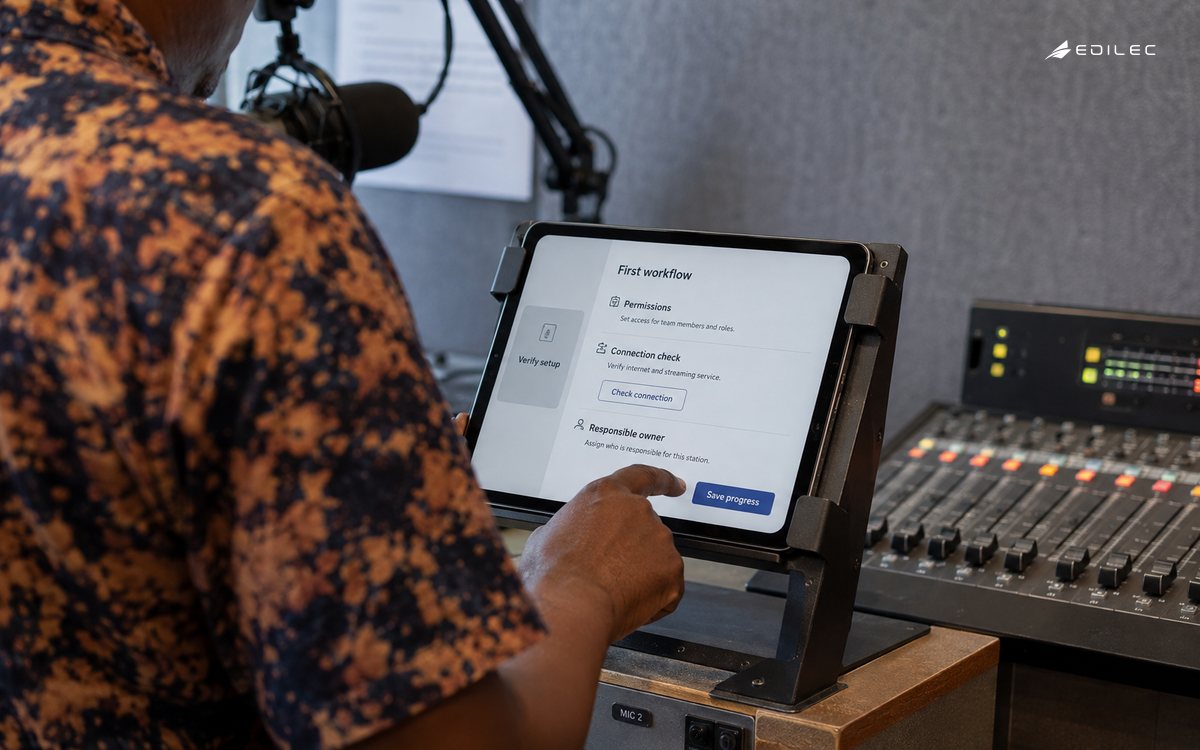A community radio volunteer verifies setup from a mounted tablet.